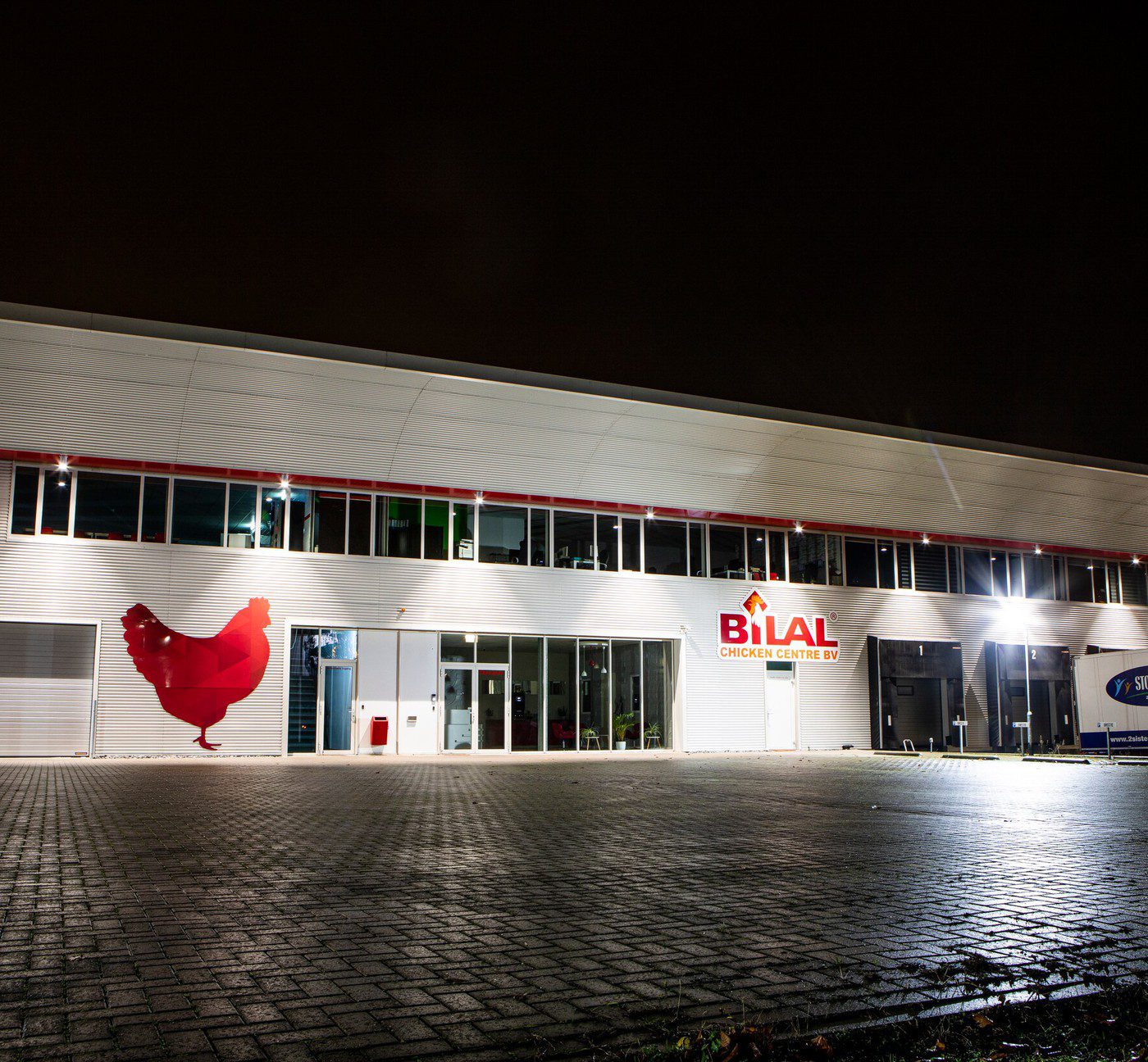 Bilal Chicken Centre - de verlichte gevel bij avond
